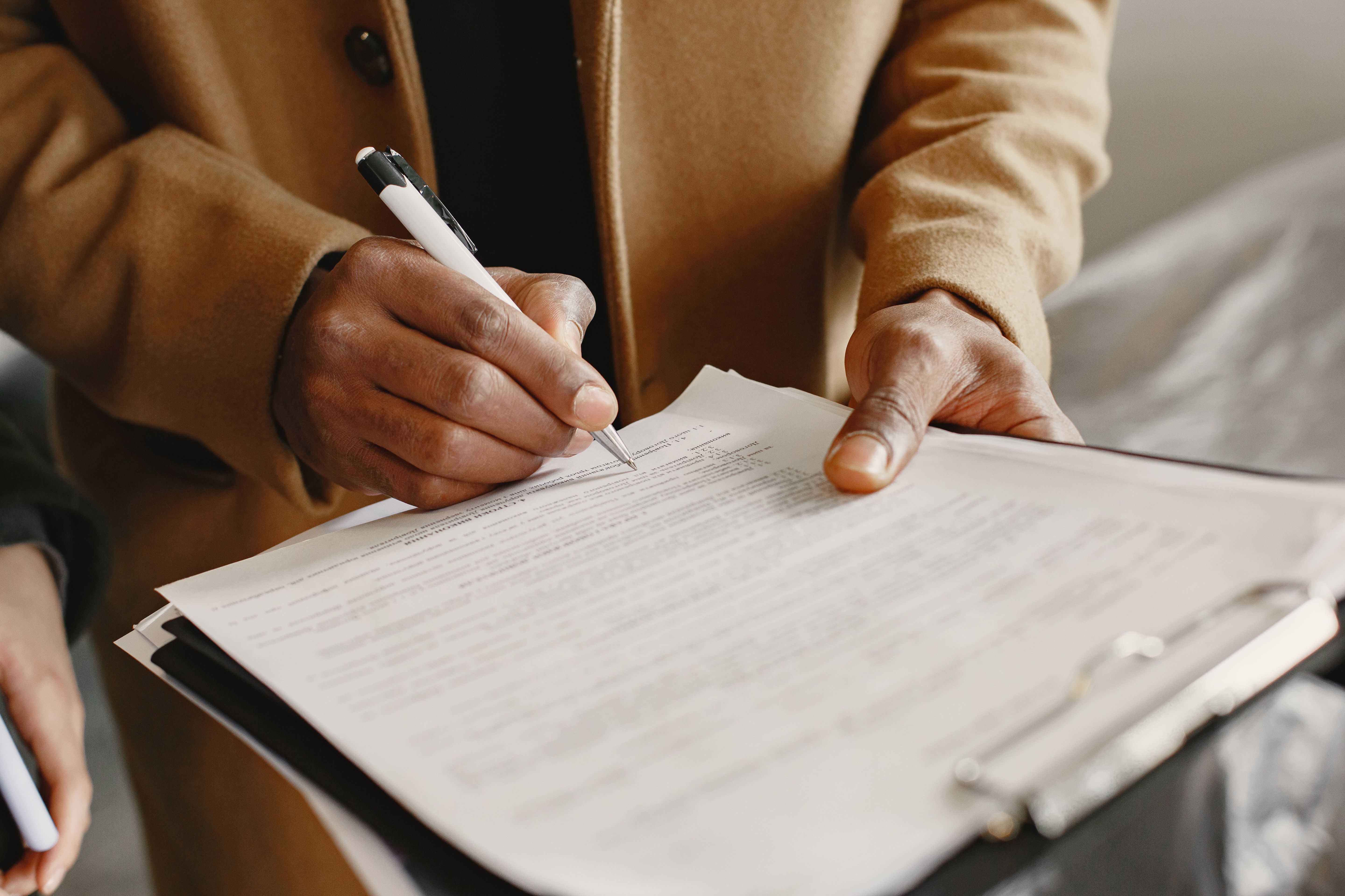 Person signing a lease agreement on a clipboard